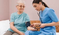 A senior woman having her bp done by the female caregiver 