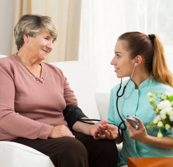 A female caregiver monitoring the blood pressure of a senior woman