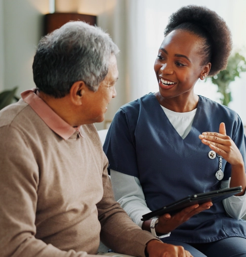 A female caregiver talking to a senior man