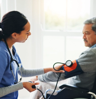 A female caregiver monitoring the blood pressure of a senior man