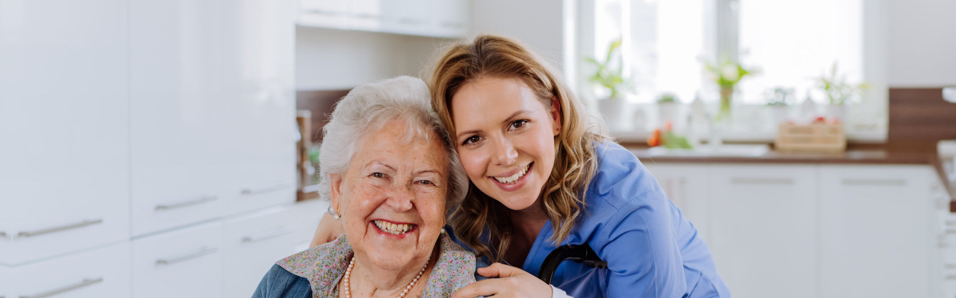 A senior woman and a female caregiver smiling together